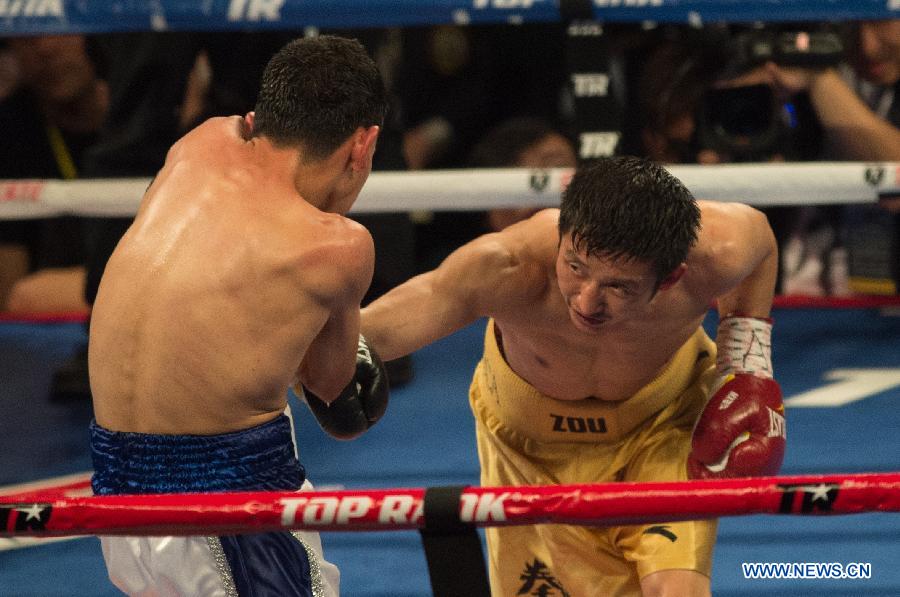 Two-time Olympic gold medalist China's Zou Shiming (R) punches during his professional debut against Mexico's Eleazar Valenzuela in Macao, China, April 6, 2013. (Xinhua/Cheong Kam Ka)