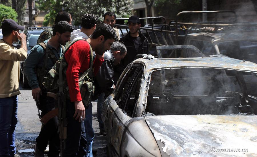 Government soldiers inspect a damaged car after mortar attacks in Damascus, Syria, April 6, 2013. Multiple mortar shells struck on Saturday several areas of Syria's capital Damascus, including a stadium and the building of the state-run al-Thwara newspaper, a pro-government radio reported. (Xinhua/Zhang Naijie) 