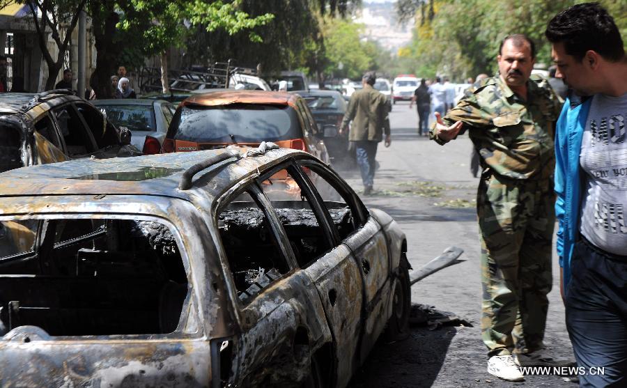 Government soldiers inspect a damaged car after mortar attacks in Damascus, Syria, April 6, 2013. Multiple mortar shells struck on Saturday several areas of Syria's capital Damascus, including a stadium and the building of the state-run al-Thwara newspaper, a pro-government radio reported. (Xinhua/Zhang Naijie) 