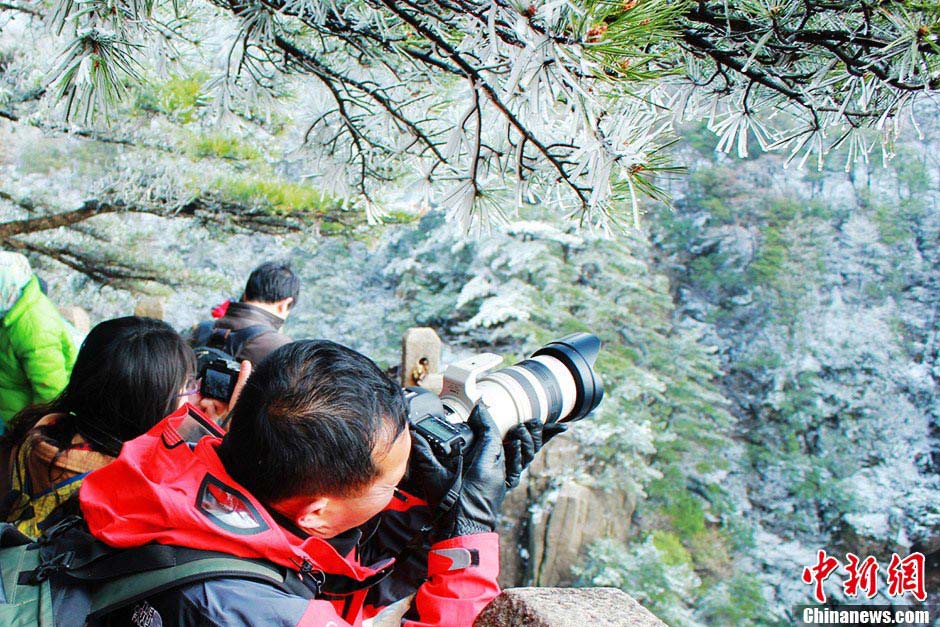 The Huangshan Mountain scenic spot in East China's Anhui Province saw a snow fall on April 6, 2013. Photo shows visitors take photos of snow-covered Huangshan Mountain. (CNS/Zhang Qifei)