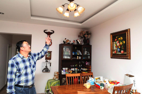 Dong Qiang points to a lamp that uses electricity generated from one of his solar panels in Tianjin, April 6, 2013. The Tianjin Binhai Electricity Company, a branch of the State Grid, recently received from Dong the first individual application to sell electricity. Dong said the electricity generated by his panels can be used for his home while remaining electricity can be sold. (Photo/Xinhua)