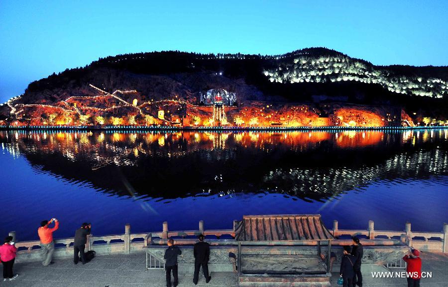 Tourists take photos of the night scenery of the scenic area of Longmen Grottoes in Luoyang, central China's Henan Province, April 8, 2013. The night tour at Longmen Grottoes, a world cultural heritage site, has been opened to public since Monday. (Xinhua/Wang Song)