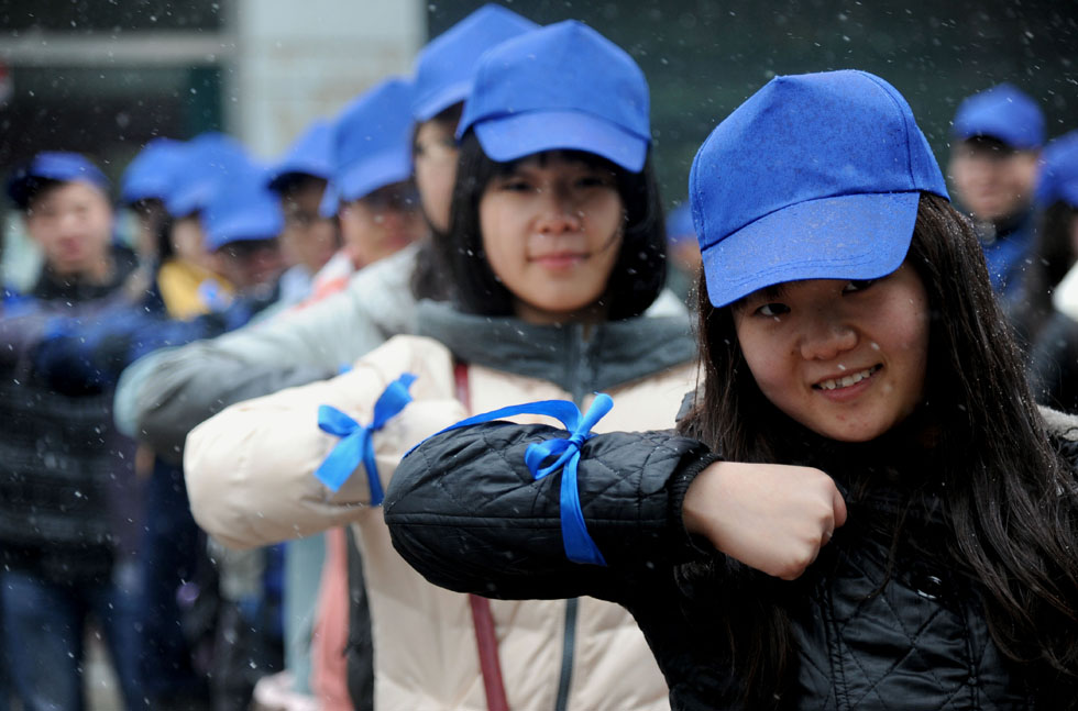Volunteers with blue ribbons on their arms from Northeastern University gather to take care of people with autism in the snow on March 31, 2013.(Xinhua Photo)