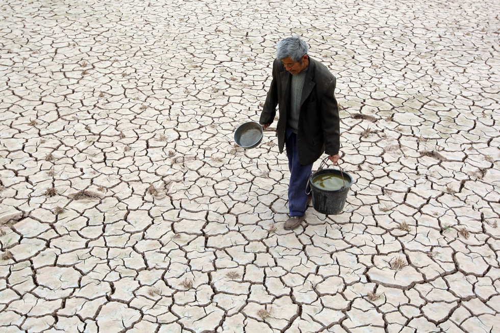Fu Xianxing, 70, a villager of Shichanggou village, walks on cracks of dried-up field in Yongxing town of Suining city in southwest China's Sichuan province, April 2, 2013. A severe drought has lingered over Suining since last winter, causing shortage of drinking water in some towns of the city. (Xinhua/Zhong Min)