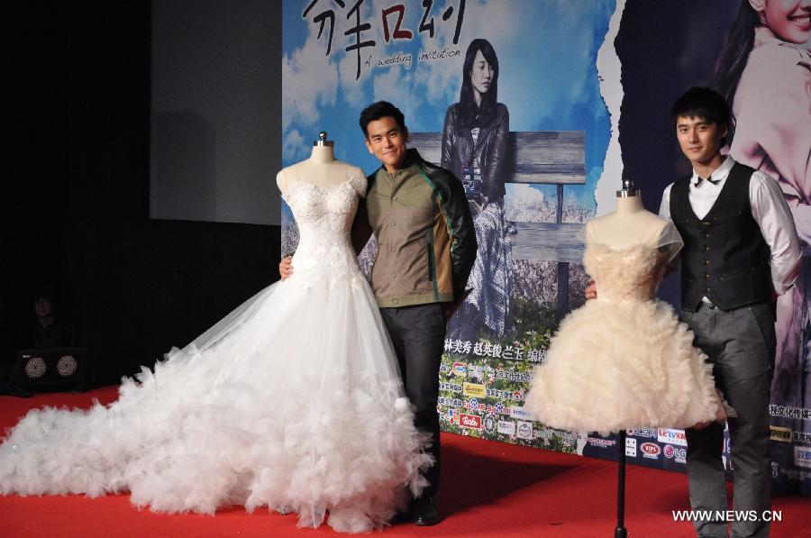 Actors Eddie Peng (L) and Jiang Jinfu pose for pictures with props used in their new movie "A Wedding Invitation" at a news conference for its premiere in Beijing, capital of China, April 9, 2013. The movie will be released on April 12, 2013. (Xinhua/Wang Junfeng)