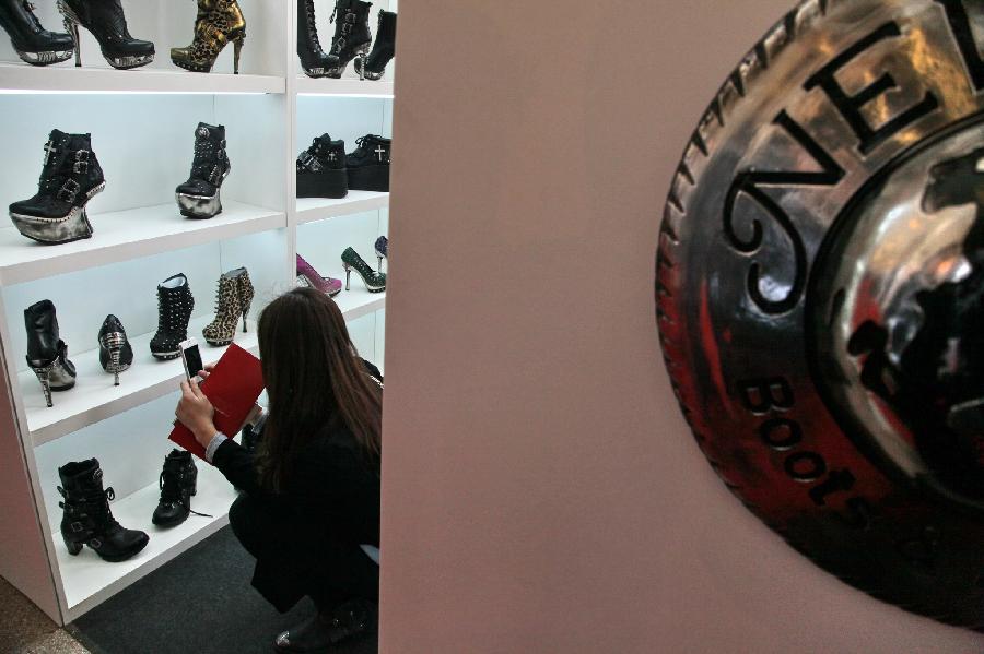 A visitor watches the displayed shoes at the MICAM Shanghai in east China's Shanghai Municipality, April. 9, 2013. The three-day fair, with the participation of some 350 exhibitors, opened here Tuesday. (Xinhua) 