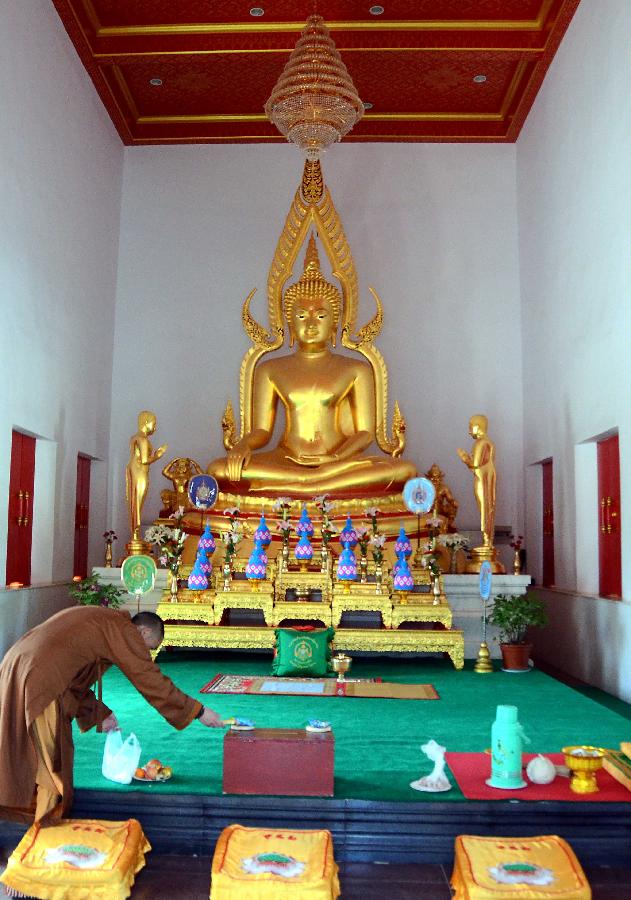 A monk puts offerings at the Thai-style Buddha hall in the Baima Temple, or the White Horse Temple, in Luoyang City, Central China's Henan Province, April 10, 2013. Visitors can see Buddha halls with different styles of foreign countries at the Baima Temple, the oldest Buddhist temple in China.(Xinhua/Wang Song)