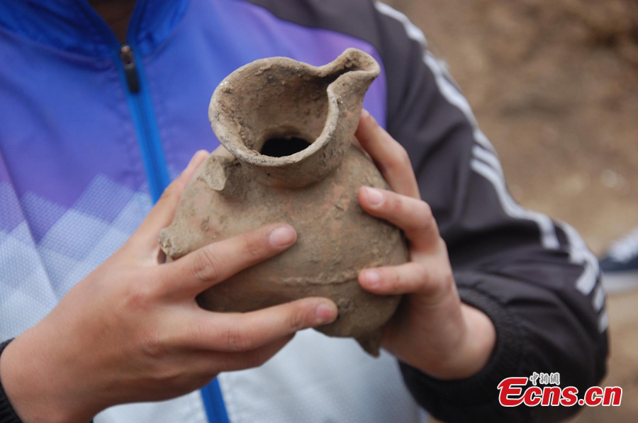 A jar is unearthed in an ancient tomb that dates back to the Longshan Period, the late period of the Neolithic Age (2900 BC to 2100 BC), in Yantai, Shandong Province, April 9, 2013. The Longshan Culture made great advancements in the area of pottery making, with black pottery being one of the more striking examples of this remarkable culture. (CNS/Jia Wei)