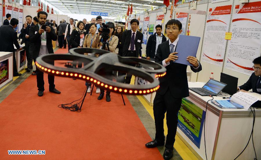 Jiang Hanpeng (2nd R) and Lei Qingyang (1st R), both from Middle School Attached to Northern Jiaotong University, demonstrate Quad Motor Helicopter Tracking System on the 41st International Exhibition of Inventions of Geneva, in Palexpo of Geneva, Switzerland, April 10, 2013. Some 50 Chinese participants came to the exhibition to display their 23 objects of invention. (Xinhua/Wang Siwei) 