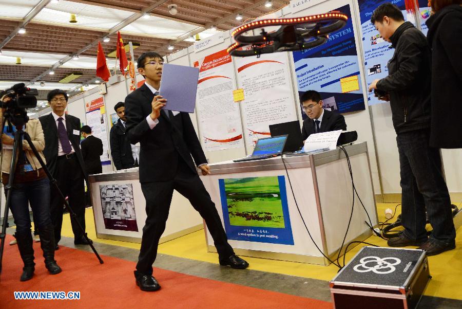 Jiang Hanpeng (3rd R) and Lei Qingyang (2nd R), both from Middle School Attached to Northern Jiaotong University, demonstrate Quad Motor Helicopter Tracking System on the 41st International Exhibition of Inventions of Geneva, in Palexpo of Geneva, Switzerland, April 10, 2013. Some 50 Chinese participants came to the exhibition to display their 23 objects of invention. (Xinhua/Wang Siwei) 