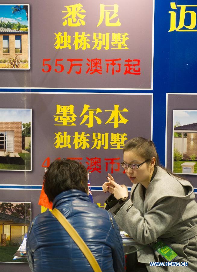 An real estate consultant introduces the information of overseas investment and immigration to a citizen during the Beijing Spring Real Estate Trade Fair in Beijing, capital of China, April 11, 2013. The four-day fair kicked off on Thursday. (Xinhua/Luo Xiaoguang)