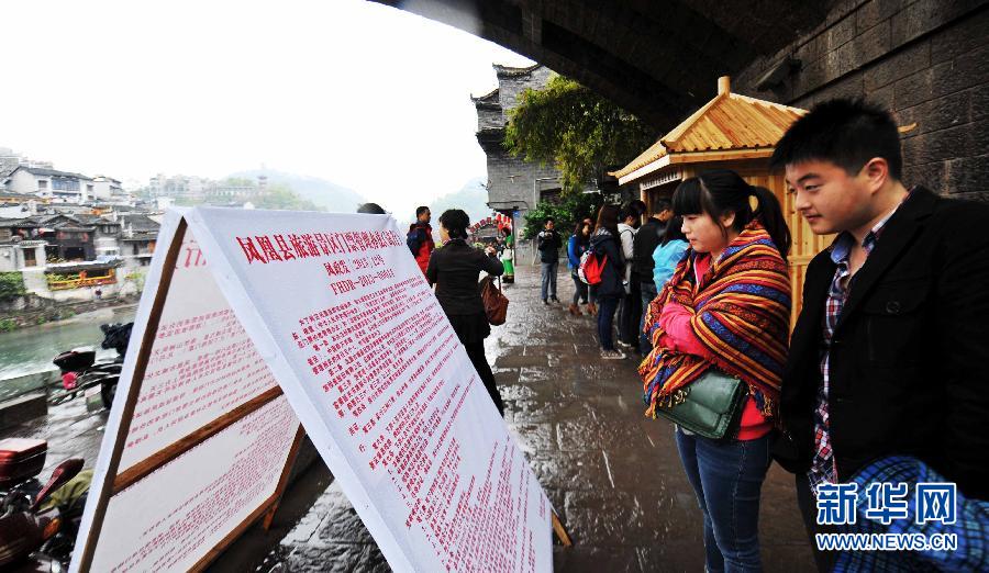 Two tourists read the ticket management rules in front of an entrance to Fenghuang, an ancient town in central China's Hunan province, April 10, 2013. (Xinhua/Zhao Zhongzhi)