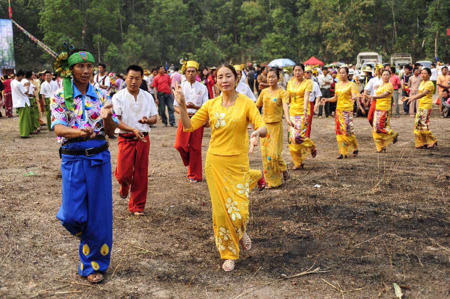 People in folk costumes dance during a celebration marking the upcoming Water Splashing Festival in Mangshi, southwest China's Yunnan Province, April 11, 2013. The Water Splashing Festival, also the New Year of the Dai ethnic group, will last for three or four days. (Xinhua/Qin Lang)