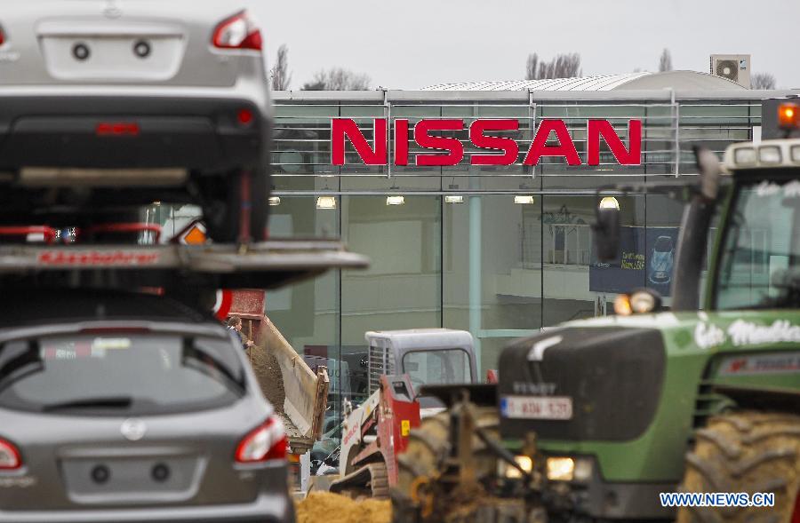A tractor passes a sales office of Japanese auto producer Nissan in Brussels, capital of Belgium, April 11, 2013. Four Japanese auto giants (Toyota, Nissan, Honda and Mazda) said Thursday they are recalling nearly 2.92 million vehicles worldwide because of airbag problems.(Xinhua/Zhou Lei)