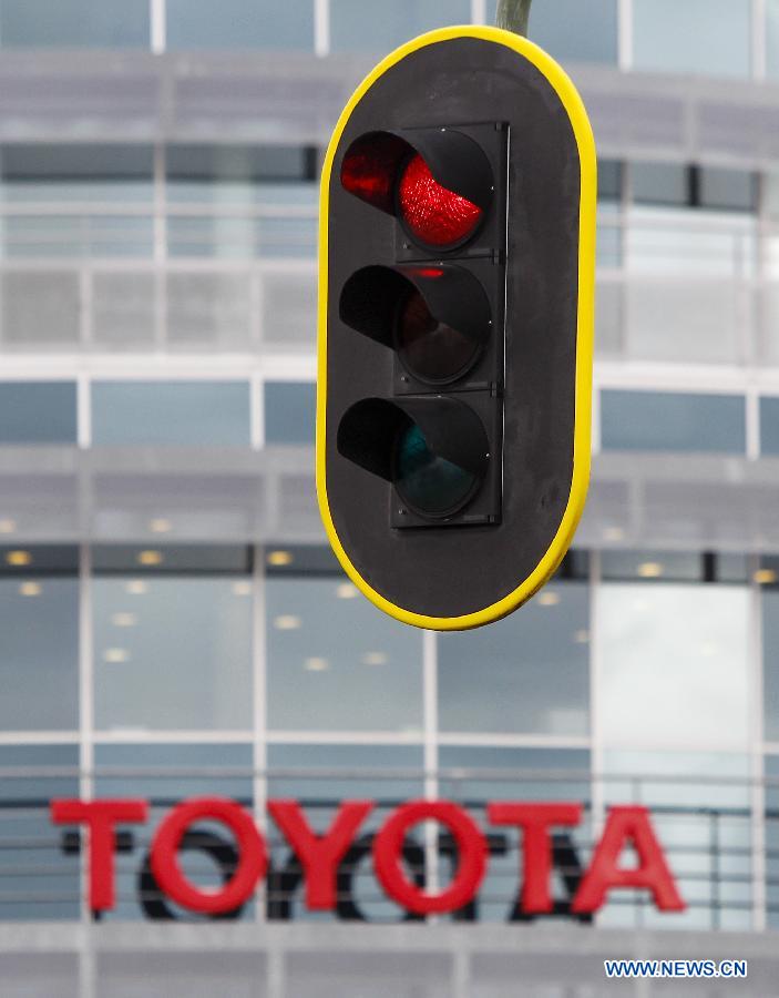 A traffic light is seen with a sign of Japanese auto producer Toyota in its background in Brussels, capital of Belgium, April 11, 2013. Four Japanese auto giants (Toyota, Nissan, Honda and Mazda) said Thursday they are recalling nearly 2.92 million vehicles worldwide because of airbag problems.(Xinhua/Zhou Lei) 