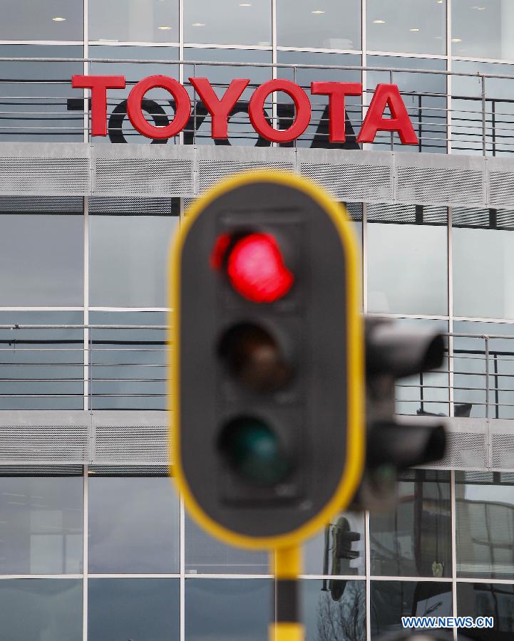 A traffic light is seen with a sign of Japanese auto producer Toyota in its background in Brussels, capital of Belgium, April 11, 2013. Four Japanese auto giants (Toyota, Nissan, Honda and Mazda) said Thursday they are recalling nearly 2.92 million vehicles worldwide because of airbag problems.(Xinhua/Zhou Lei)