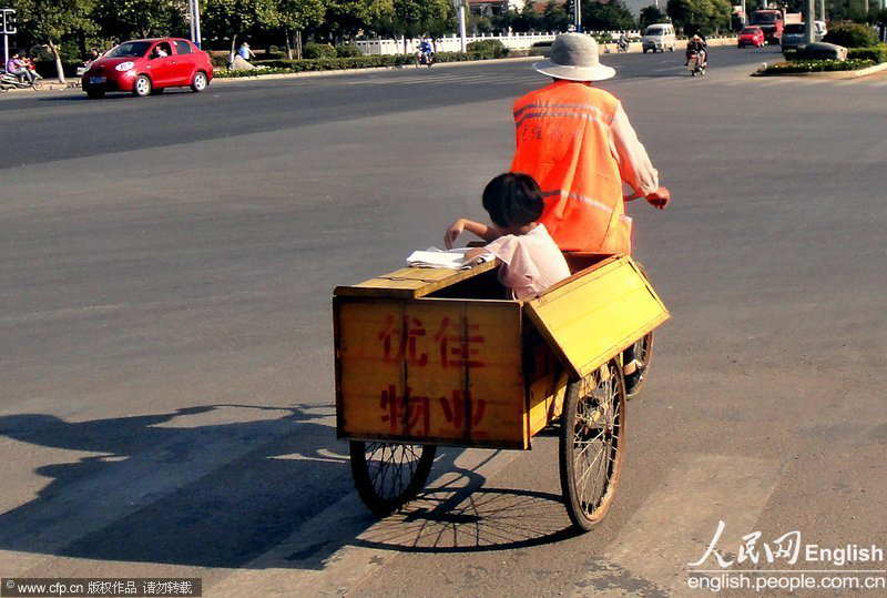 A little girl sitting in the tricycle does her homework as her grandfather rides the tricycle to go to work in Xuzhou, east China’s Jiangsu province.(Photo/ CFP) 