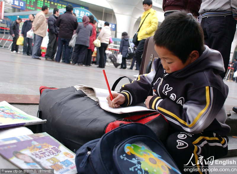 A boy does his homework on a pack of luggage in the square of Lanzhou Railway Station. (Photo/ CFP) 