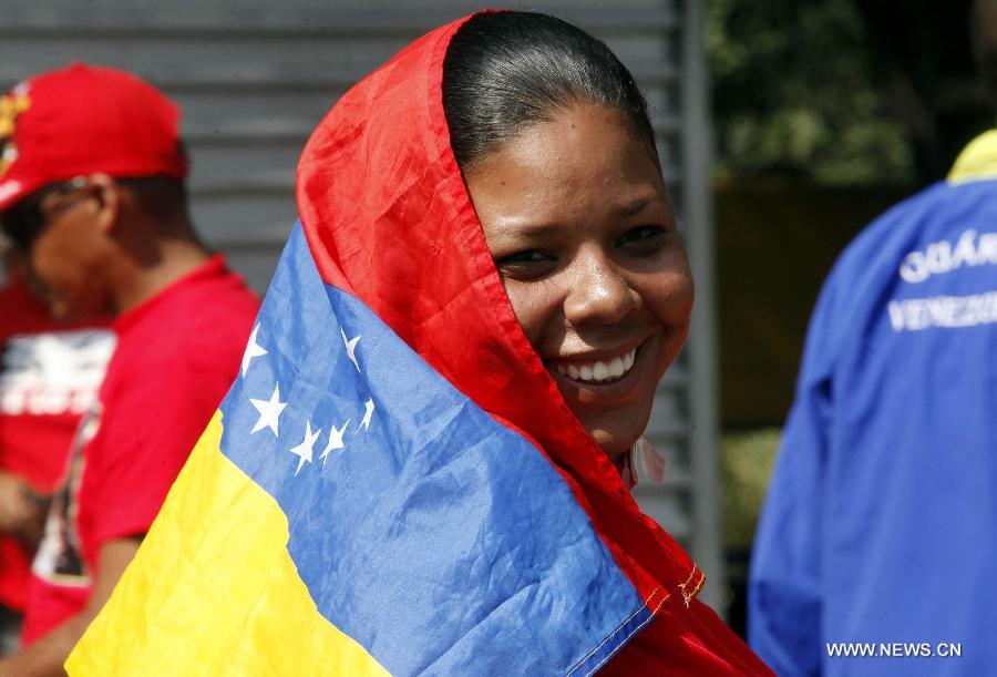 A resident covers her head with a national flag during the closing campaign of Venezuelan acting president and presidential candidate Nicolas Maduro in the city of Caracas, capital of Venezuela, on April 11, 2013. (Xinhua/AVN) 