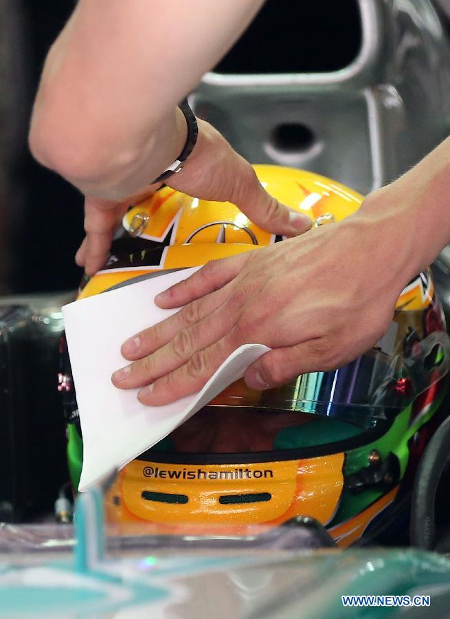 A crew member cleans the helmet of Mercedes driver Lewis Hamilton after the first practice session of the Chinese F1 Grand Prix at the Shanghai International circuit, in Shanghai, east China, on April 12, 2013. (Xinhua/Li Ming)