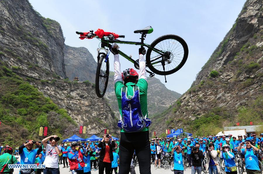 A cyclist lifts his bike after winning a prize at the Shaohua Mountain National Forest Park in Xi'an, capital of northwest China's Shaanxi Province, April 12, 2013. Over 300 cyclists participated a campaign advocating low-carbon ecotourism by riding bikes here on Friday. (Xinhua/Ding Haitao)