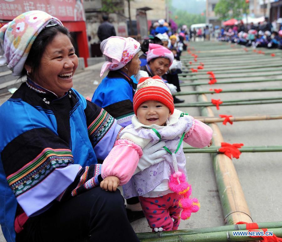 A woman of Dai ethnic group watches the performance with her grandson during a folk custom and culture festival marking the "San Yue San" (the third day of the third lunar month in Chinese Calendar) in Shizong County, southwest China's Yunnan Province, April 12, 2013. The festival, attracting tens of thousands of local residents and tourists from both at home and abroad, was held here Friday. (Xinhua/Yang Zongyou)