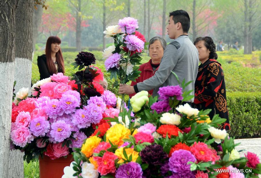 A vendor sells silk flowers of peony at a park in Luoyang, central China's Henan Province, April 3, 2013. Known as the "city of peony", Luoyang has created an industry chain on peony in recent years. Various crafts and products of peony have been developed to serve the local economy. (Xinhua/Wang Song)
