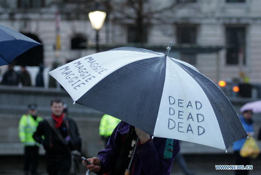 A protester holds an umbrella during a party marking former British Prime Minister Margaret Thatcher's death in central London's Trafalgar square, on April 13, 2013. Parties staged by opponents of Margaret Thatcher to celebrate her death took place in several locations across the UK on Saturday. (Xinhua/Bimal Gautam) 