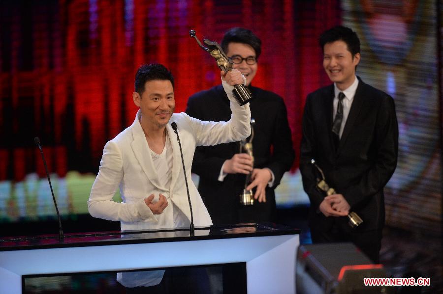 Singer Jacky Chang (L) lifts up the trophy after receiving the Best Original Film Song award by singing the song "Dingfengbo" for the movie "The Last Tycoon" at the presentation ceremony of the 32nd Hong Kong Film Awards in south China's Hong Kong, April 13, 2013. (Xinhua/Chen Xiaowei)