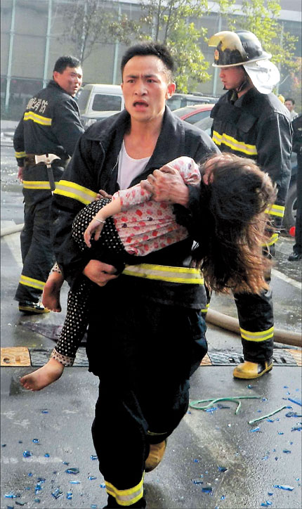 A girl is carried to safety from a hotel fire that killed at least 14 people and injured 50 others yesterday. Some of the injuries were serious, officials said. A fire at an Internet cafe spread to the hotel on the building's upper floors in central China's Xiangyang City. The blaze broke out just after 6:30am and firefighters didn't manage to put it out until almost 9am. Some of the hotel's guests managed to escape while others were rescued by firefighters. The hotel said that 42 of its 50 rooms were occupied at time of the fire. The cause of the blaze is still under investigation.(Shanghai Daily)