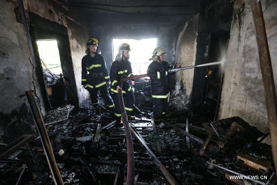 Firefighters work at the accident site after a fire broke out in a hotel in the Fancheng District of Xiangyang City, central China's Hubei Province, April 14, 2013. Fourteen people have been confirmed dead and 50 others injured in the hotel fire that occurred on Sunday morning. (Xinhua) 