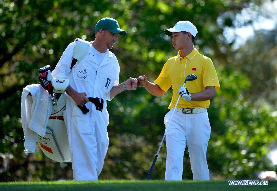 China's Guan Tianlang (R) fist bumps caddie Brian Tam on on the fourth hole during the third round of the 2013 Masters golf tournament at the Augusta National Golf Club in Augusta, Georgia, the United States, April 13, 2013. Guan shot a five-over par 77 Saturday. (Xinhua/Charles Laberge/Augusta National)