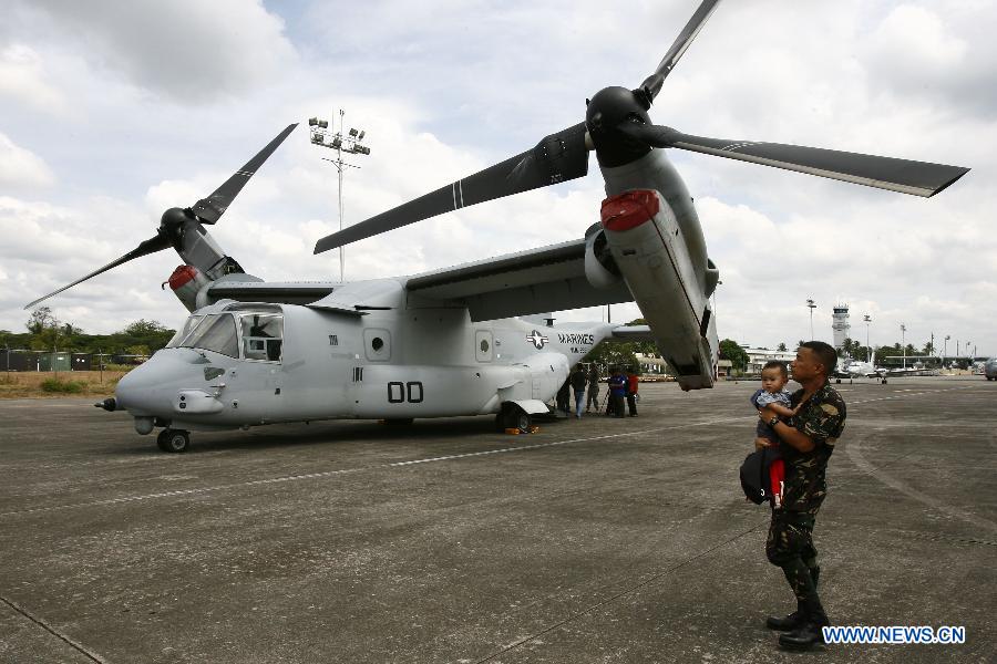 A Philippine Air Force soldier carries his son in front of the MV-22 Osprey during an aircraft static display as part of a joint military exercise in Pampanga Province, the Philippines, April 13, 2013. The Philippines and the U.S. held their 29th annual joint military exercise with at least 8,000 American and Filipino soldiers participating in the training. The joint military exercise, more known as Balikatan, which means "shoulder-to-shoulder" in Filipino, is held from April 5 to 17. (Xinhua/Rouelle Umali)