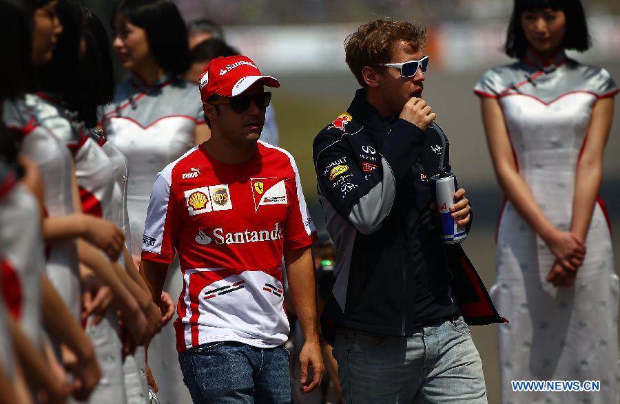 Red Bull driver Sebastian Vettel (2nd, R) of Germany and Ferrari driver Felipe Massa (3rd, R) of Brazil react before attending the drivers parade prior to the start of the Chinese F1 Grand Prix at the Shanghai International circuit, in Shanghai, east China, on April 14, 2013. (Xinhua/Li Ming)
