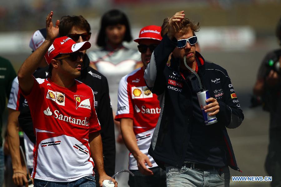 Red Bull driver Sebastian Vettel (Front, R) of Germany and Ferrari driver Felipe Massa (Front, L) of Brazil greet the audience before attending the drivers parade prior to the start of the Chinese F1 Grand Prix at the Shanghai International circuit, in Shanghai, east China, on April 14, 2013. (Xinhua/Li Ming)