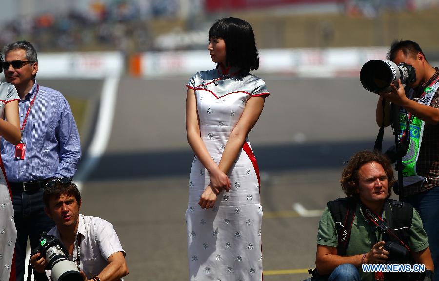 A model (C) reacts during the drivers parade prior to the start of the Chinese F1 Grand Prix at the Shanghai International circuit, in Shanghai, east China, on April 14, 2013. (Xinhua/Li Ming)