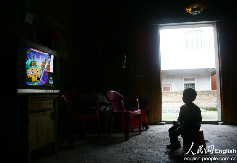 The younger boy watches TV to kill time on April 3, 2013. TV has become a spiritual sustenance of daily life for both the child and his father. The eldest son was also diagnosed with AIDS, but was not refused by the school. (CFP/Pan Deng)