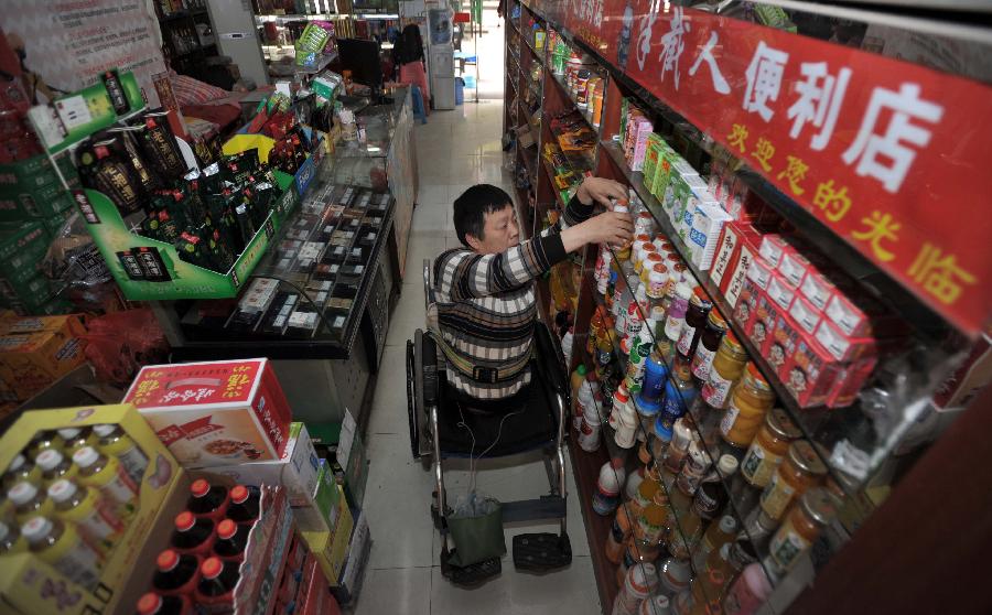 Peng Shuilin tidies up the shelves at his convenience store. (Xinhua/ Li Ga)