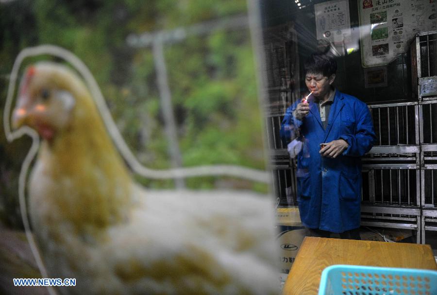A trader surnamed Ye smokes in front of empty chicken coops in a fowl trade area at a market in Hangzhou, capital of east China's Zhejiang Province, April 15, 2013. The city banned all trade of live fowl and closed its bird markets in its main urban areas to avoid infection of H7N9 avian flu, according to the city's announcement on April 14. (Xinhua/Han Chuanhao)