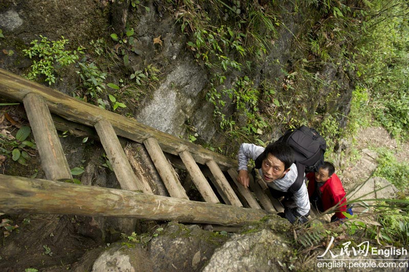 Journalists from a local newspaper climb the ladders to visit the village of Sangzhi county, Hunan province April 11, 2013. (Photo/ People's Daily Online)