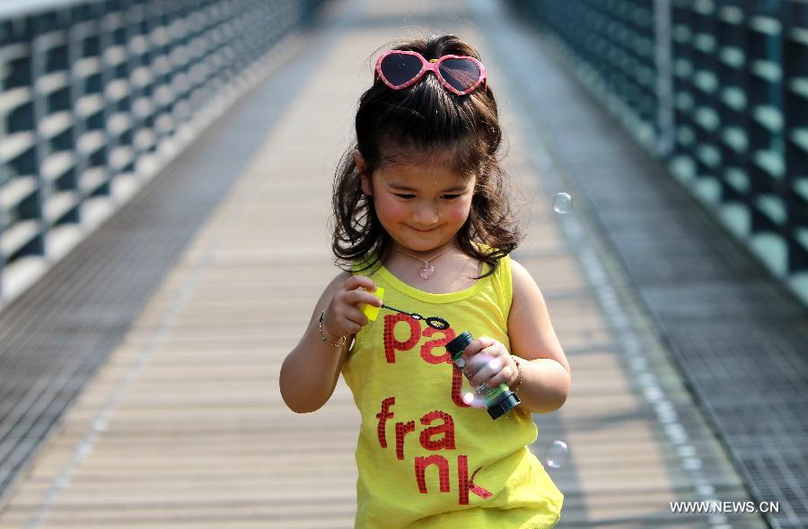 A girl plays with bubbles in a park in Xujiahui area of Shanghai, east China, April 15, 2013. The temperature in Shanghai's Xujiahui area reached 30.2 degrees Celsius due to a warm air mass over it on Monday, according to local meteorological station. (Xinhua/Pei Xin) 