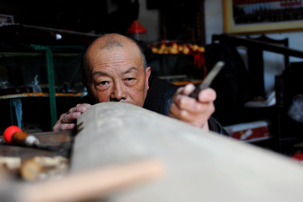 Wang Zhanyun, 65, is making a Fuxi Guqin, an ancient Chinese stringed instrument in his Chinese-decorated studio on April 10, 2013.  Wang is a well-known inheritor of Fuxi intangible cultural heritage who has been working on Guqin for over 40 years. It usually takes 2-3years to finish a Guqin since the production process is very exquisite and complex. (Photo by Chen Bin/ Xinhua)