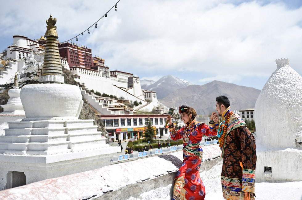 A couple wearing Tibetan costumes pose for wedding photo in front of the Potala Palace in Lhasa, capital of southwest China's Tibet Autonomous Region, April 7, 2013. The ancient city of Lhasa has witnessed many couples’ promise of love.  (Photo/Xinhua)
