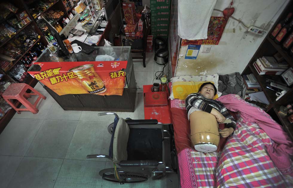 Peng Shuilin, 55, survives miraculously though his body was cut half by a truck in an accident in 1995. He has been running a convenience store with local government's supports since 2007. Photo shows that Peng wears "special equipment" to protect his body. (Xinhua/ Li Ga) 