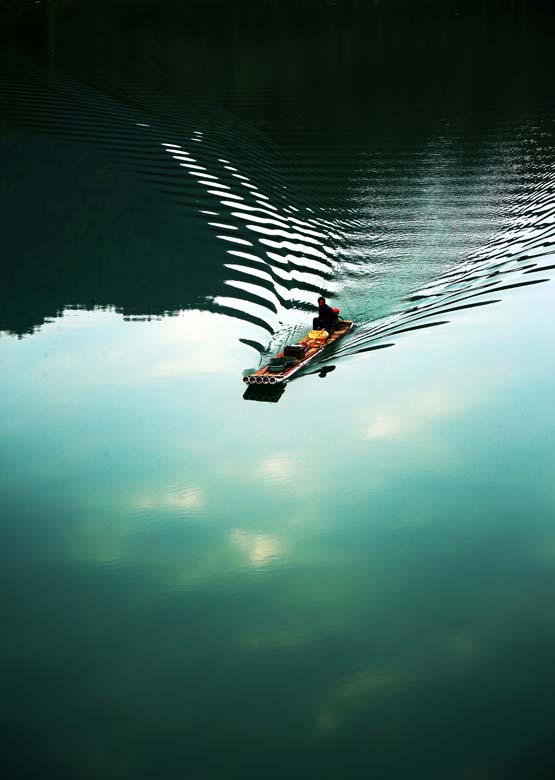 A fisherman rides a bamboo raft on the Li River, slicing the water on April 7, 2013.(Photo/Xinhua)