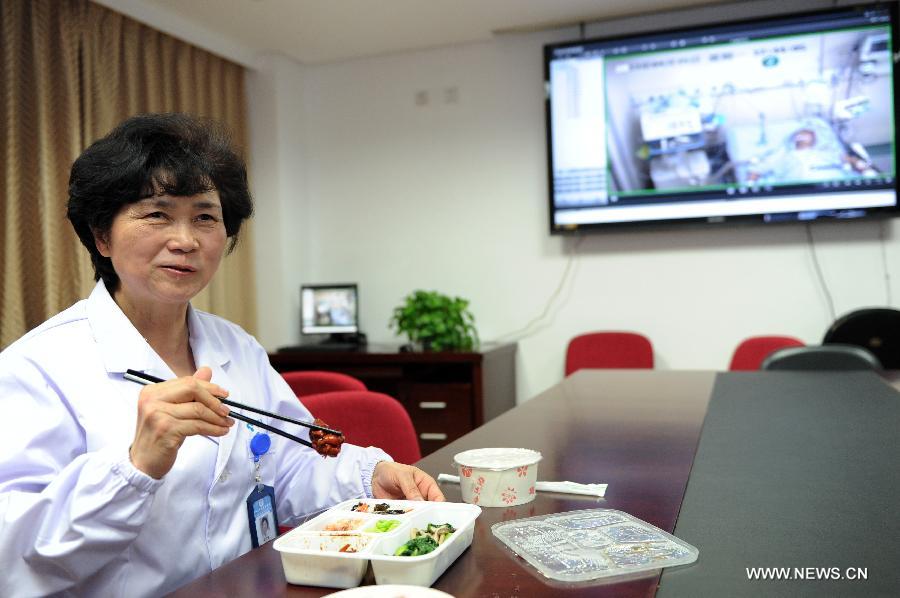 Li Lanjuan, an academician of Chinese Engineering Academy and director of the State Key Laboratory for Diagnosis and Treatment of Infectious Diseases, eats chicken thigh meat in her box lunch in Hangzhou, capital of east China's Zhejiang Province, April 15, 2013. (Xinhua/Ju Huanzong)