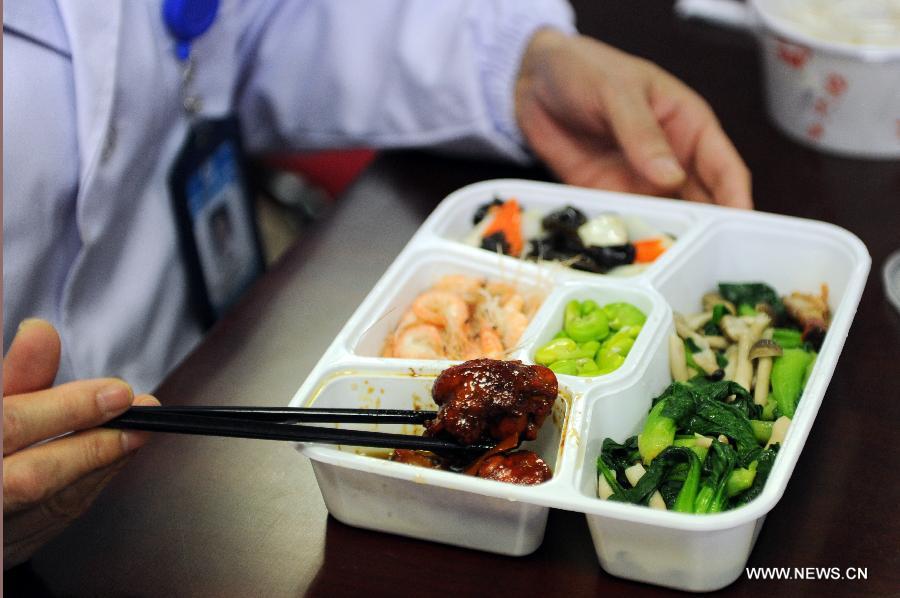 Li Lanjuan, an academician of Chinese Engineering Academy and director of the State Key Laboratory for Diagnosis and Treatment of Infectious Diseases, eats chicken thigh meat in her box lunch in Hangzhou, capital of east China's Zhejiang Province, April 15, 2013. (Xinhua/Ju Huanzong)