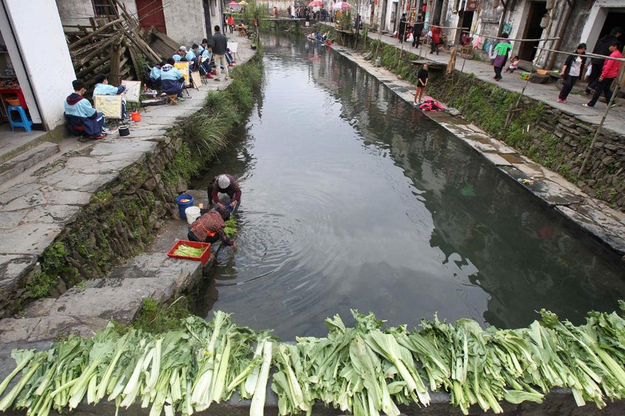 Students from Hang Zhou sketch drawings in Likeng village, Tuochuan township, Wuyuan county. At the river's edge vegetables are hung out to dry where villagers wash and clean them on April 8, 2013. (Xinhua)