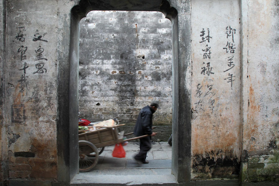 A Likeng villager in the Tuochuan township of Wuyuan county, pulls a cart through an alley of an ancient dwellings on April 8, 2013. (Xinhua)