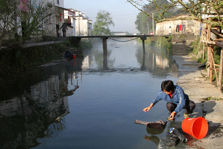 A woman in Likeng village in the Tuochuan township of Wuyuan county, washes clothes in the river, April 7, 2013. (Xinhua)